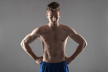 Attractive young man with perfect body standing against blue-gray background