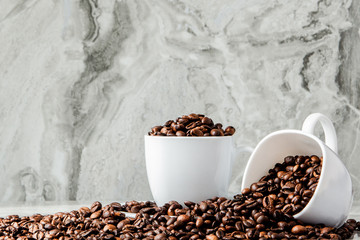 Black coffee in cup and coffee beans on marble background. Top view, space for text