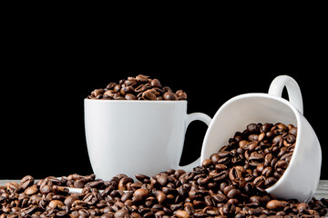 Black coffee in white cup and coffee beans on black background. Top view, space for text