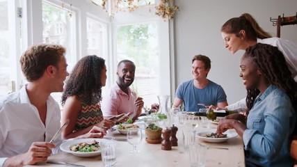 Waitress Serving Wine To Group Of Friends Eating Meal In Restaurant Together 