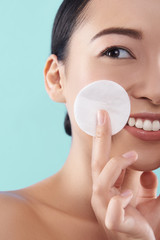 Cute pretty lady with fresh skin touching her cheek with cotton sponge