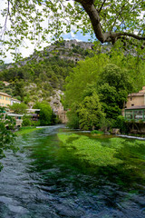 Fototapeta premium South of France, view on small Provencal town of poet Petrarch Fontaine-de-vaucluse with emerald green waters of Sorgue river