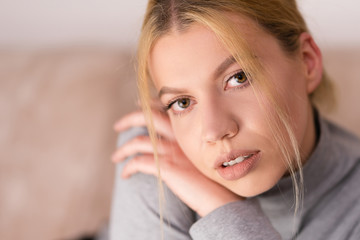 Portrait of beautiful young woman with blonde hair looking to the camera at home