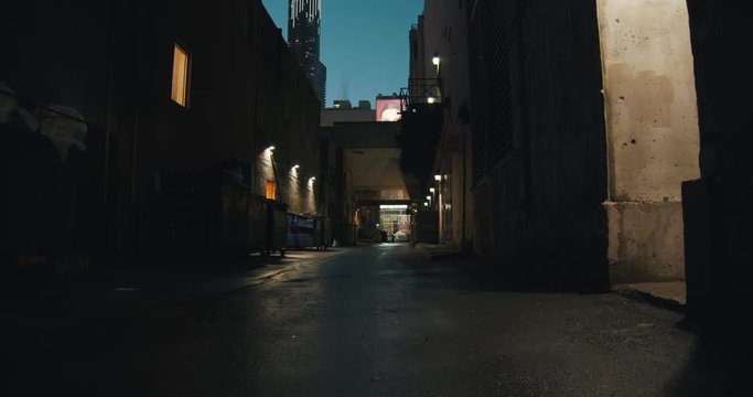 Establishing shot of a dark alleyway at night. Atmospheric 4K footage. Shot on a cinema camera in RAW. No discernible faces or logos.