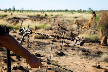 A man fixes a broken fence using wire strainers and fencing pliers