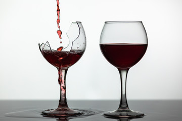 Red wine pouring into broken wine glass on the wet surface. Rose wine pour