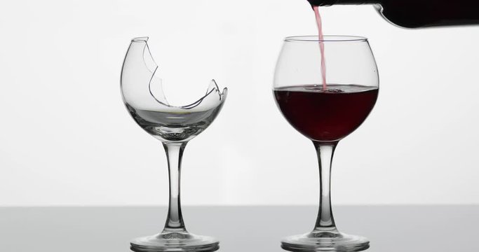 Wine. Red wine pouring into normal and broken wine glasses on the wet surface