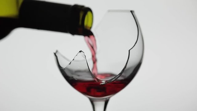 Wine. Red wine pouring in broken wine glass on the white background
