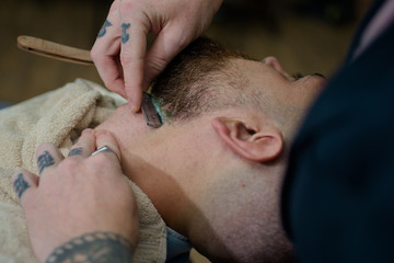 Obraz na płótnie Canvas Hair Stylist and Barber. Hairdressers work for a handsome guy at the barber shop. Barber scissors and straight razor barber shop. Male client getting haircut by hairdresser.