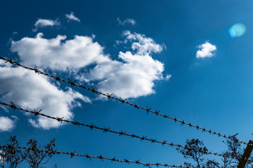 barbed wires and large fence, created to block immigrants, barbed wires and blue sky