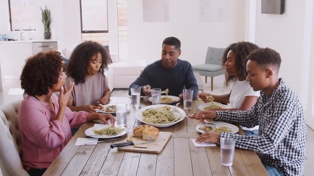 Elevated view of black family sitting at dinner table talking as they eat together, close up