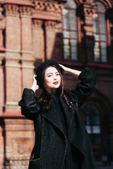 Naklejka premium A girl in a black coat walks down the street