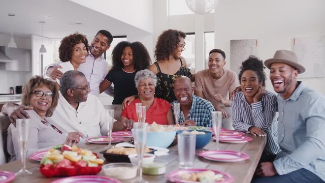 Large three generation black family group portrait at dinner table during a celebration at home