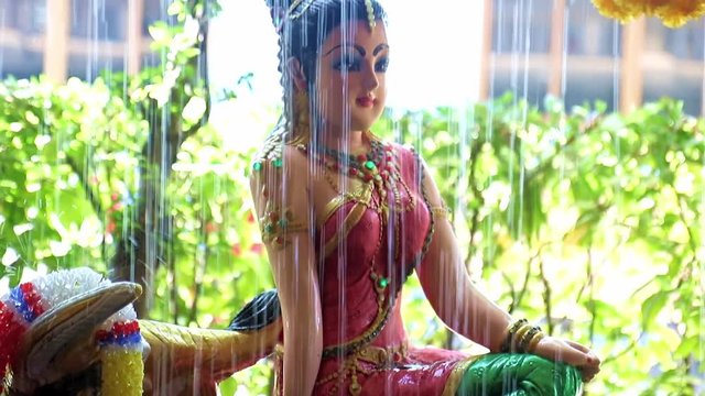 Phra Mae Thorani, goddess from Buddhist mythology, behind water of fountain.