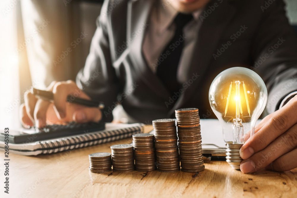 Poster business man hand holding lightbulb with using smartphone and calculator to calculate and money stac