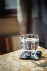 Glass of water on the table with reflections on it