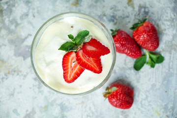 Ice cream with strawberries in a glass vase. Gray textured background. Dessert