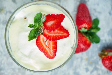 Ice cream with strawberries in a glass vase. Gray textured background. Dessert