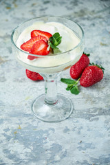 Ice cream with strawberries in a glass vase. Gray textured background. Dessert