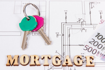 Inscription mortgage with keys and money on construction diagrams of house