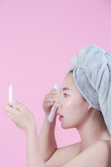 Asian beautiful woman cleans the face on a pink background.