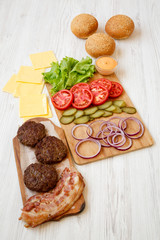 Cheeseburger ingredients on a white wooden background, side view. Close-up.