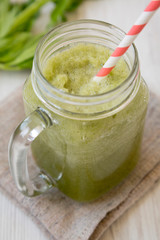 Glass jar mug filled with celery smoothie over white wooden background, side view. Close-up.