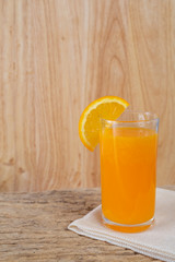 Glass of orange juice placed on wood.