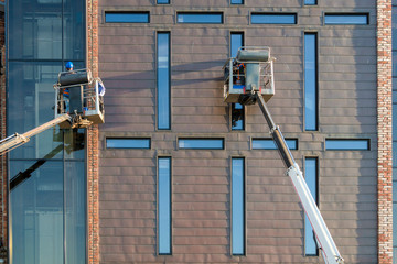 Window cleaner works at a height from the lift. Work in the evening at sunset. Fulfill an order. 