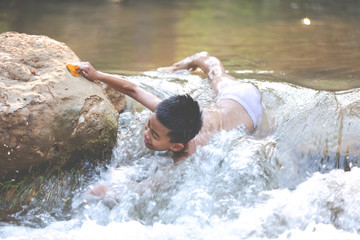 The boys are playing the waterfall in a fun way.