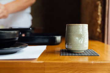 Japanese ceramic cup of green tea on wooden table.