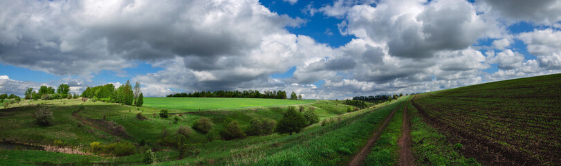 Beautiful panoramic landscape with ground country road passing through the green fields and hills