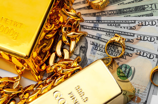 Jewelry Buyer, Pawn Shop And Buy And Sell Precious Metals Concept Theme With A Pile Of Cash In US Dollars, Golden Rings, Necklace Bracelet And Gold Bullion Isolated On White Background