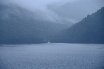 Fototapeta na wymiar Early morning mist rolling down to the sea in Milford Sound