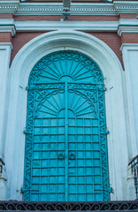 Blue metal door of an old building with a black metal staircase. Entrance to the church