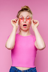Photo of surprised blonde in pink t-shirt holding her glasses