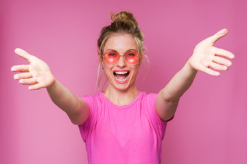 Photo of cheerful blonde in pink T-shirt with arms stretched forward