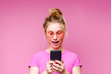 Photo of blonde in pink T-shirt with phone in her hands