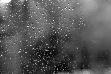 Raindrops on glass in rainy weather close up. Natural background black and white