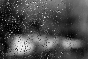 Raindrops on glass in rainy weather close up. Natural background black and white