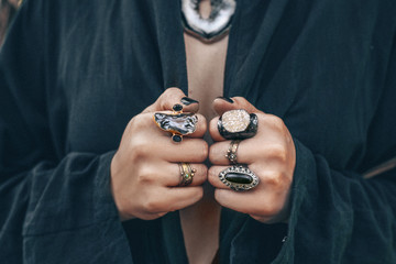 close up of woman hands with boho gem stones rings
