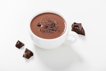 Hot chocolate drinks and chocolate pieces in white cup.