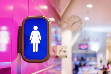 Toilets icon. Blue public restroom signs with a female symbol. Interior of airport terminal.