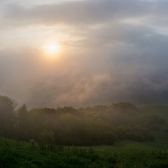 The rising sun lightening the mountain range through the clouds