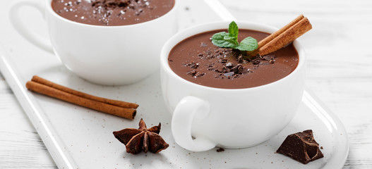 Hot chocolate drinks and chocolate pieces in white cup.