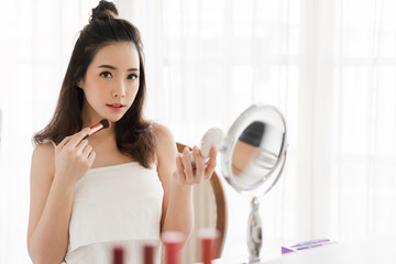 Smiling young beautiful asian woman fresh healthy skin  holding make-up brushes with cosmetics set at home.facial beauty and cosmetic concept