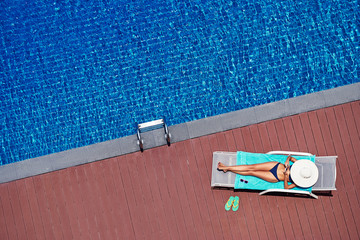 Enjoying suntan. Vacation concept. Top view of slim young woman in bikini on the sun lounger near ...