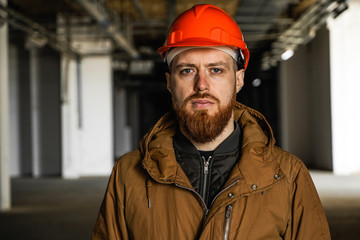 The average plan portrait of an adult man in a helmet with redhead, evaluates, studies, looks into the frame, horizontal, free space and perspective