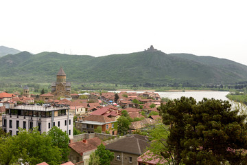 Fototapeta na wymiar Mtskheta - ancient capital of Georgia. Top view of old town with Jvari Monastery Hill and Svetitshoveli Cathedral