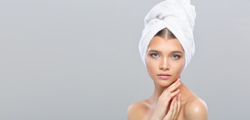 Beautiful young woman with perfect skin with a towel on her head, isolated on a gray background. - 268466008
